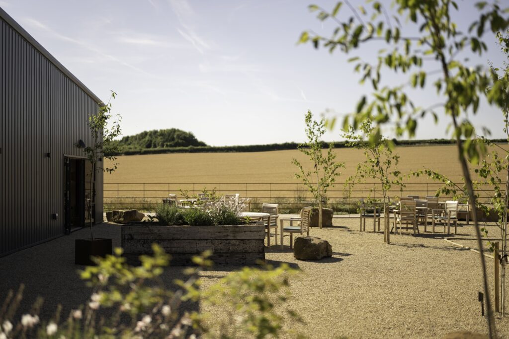 Sunny terrace with boules court at Barnsgrove private members clubhouse in Hampshire