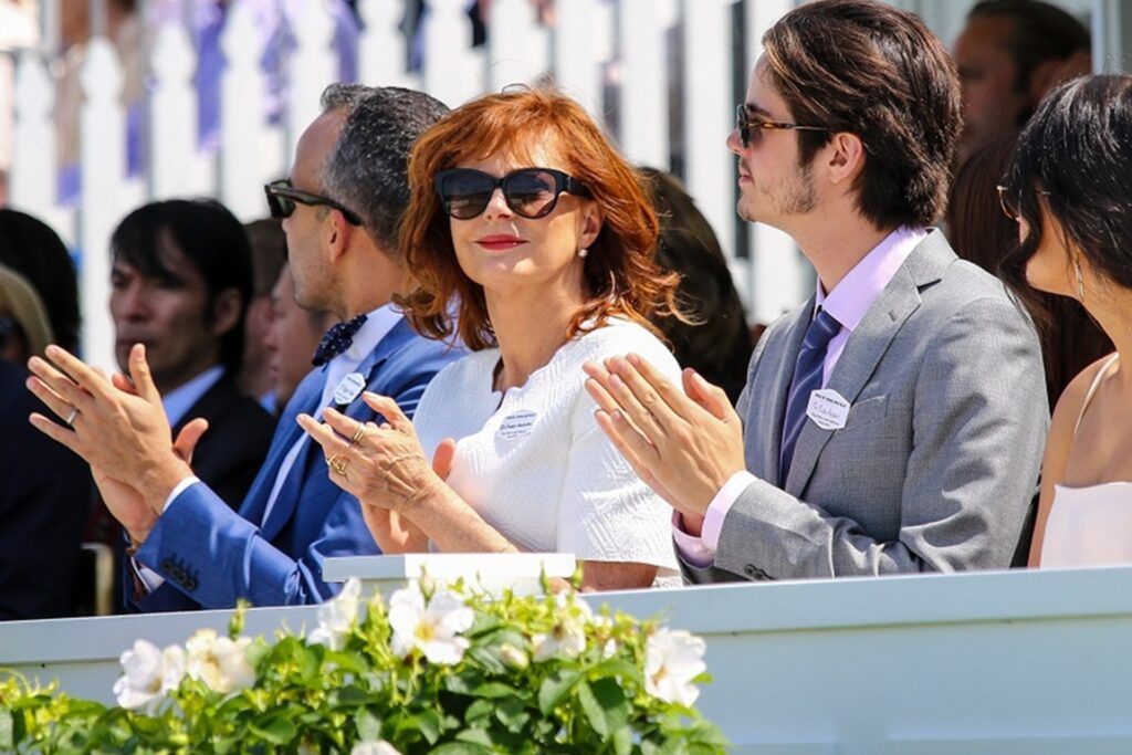 Crowd clapping at a polo match at Guards Polo Club and a picture of Susan Sarradon